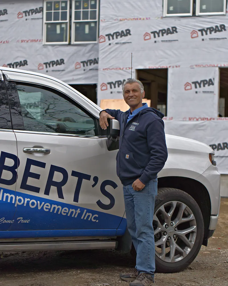 Carlos Robert standing next to his company truck on a job site