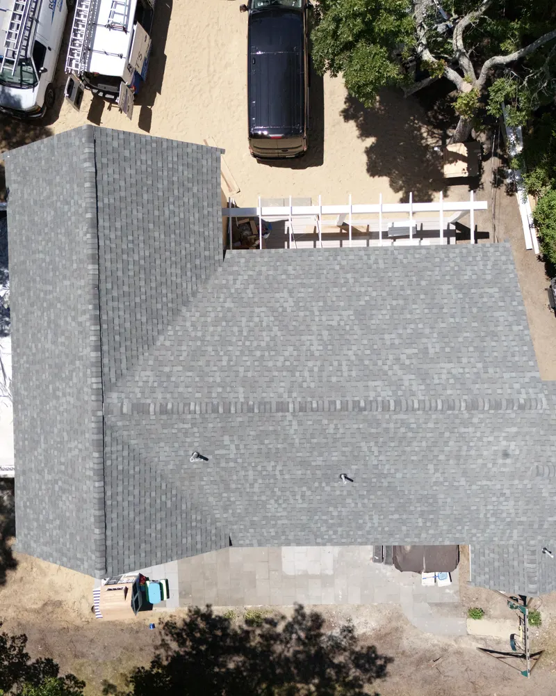 Drone view from above of a new gray architectural shingle roof on a Cape Cod house